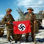 These two Canadian soldiers raise a Nazi flag which they captured in a quarry south of Hautmesnil, France. (August 10, 1944). Source: National Archives of Canada.