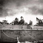 A U.S. Coast Guard coxswain named "Jim" is at the helm of a landing craft vehicle carrying troops from the 4th Infantry Division toward Utah Beach on D-Day. Source: U.S. National Archives, # 26-G-2349.