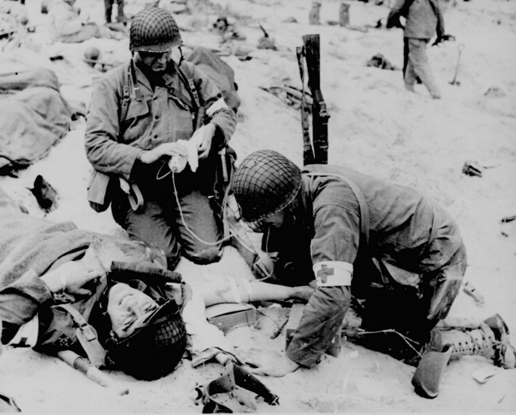 Medic helping injured soldier. France. (1944). Source: U.S. National Archives, # 208-YE-22.