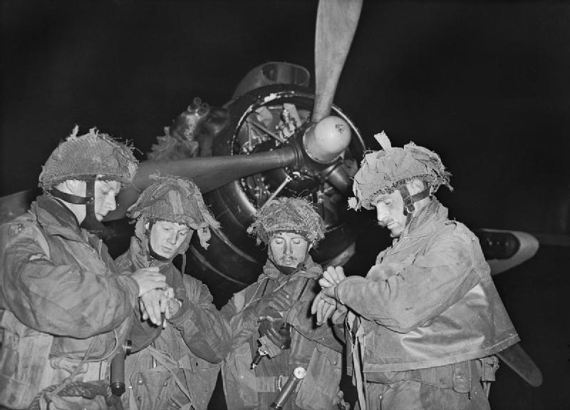 Operation Tonga. 4 'stick' commanders of 22nd Independent Parachute Company, British 6th Airborne Division, synchronize their watches at about 11 p.m. prior to take off from RAF Harwell, Oxfordshire. Officers, left to right: Bobby de la Tour, Don Wells, John Vischer, Bob Midwood. (June 5, 1944). Source: Imperial War Museums,  H 39070.