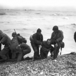 Members of a landing party help injured soldiers to safety on Utah Beach during the Allied Invasion of Europe on D-Day. (June 6, 1944). Source: Army.mil.
