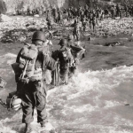 Troops of the 5th Engineer Special Brigade, wade through the surf to the northern coast of France, at Fox Green, Omaha Beach in order to bolster the forces after D-Day. (June 8, 1944). Source: U.S. National Archives, # 111-SC-190248.