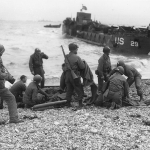 Troops give first aid to survivors of sunken landing craft on D-Day. (June 6, 1944). Source: U.S. National Archives, # SC 320870.