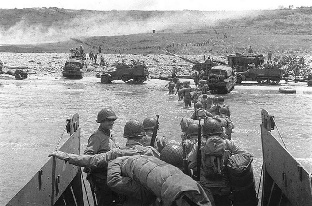 Troops wade ashore from an LCVP on Omaha Beach. (June 6, 1944). Source: U.S. National Archives, # SC 320902.