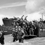 American reinforcements pile from a Coast Guard landing barge into the surf on the French coast. They will replace the fighting units that secured the Normandy beachhead and spread north toward Cherbourg. Source: U.S. National Archives, # 26-G-2409.