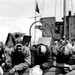4 Coast Guardsmen, proceeding as scouts in an LCM to the French invasion beach shortly before H-hour, get their heads together and display their full accord with General Sherman on the subject of war ("War is hell"). Source: U.S. National Archives, # 26-G-2410.