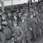 Long lines of Nazi prisoners are marched from a British landing craft at a wharf at an undisclosed English port. Source: U.S. National Archives, # 26-G-2359.