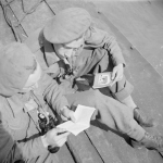 British troops study French guidebooks onboard LCT 610 taking 13th/18th Royal Hussars to Normandy. (June 4 or 5, 1944). Source: Imperial War Museums,  B 5109.