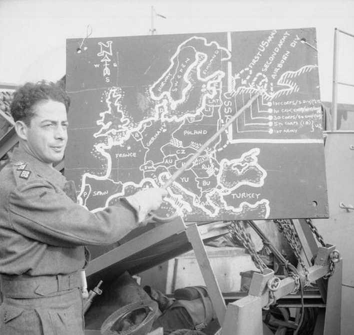 Captain Lasdun of 693 Road Construction Co., Royal Engineers, uses a blackboard to brief the men aboard LST 406 at a south coast port. (June 4, 1944). Source: Imperial War Museums, B 5157.