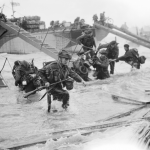 Royal Marine Commandos of the 4th Special Service Brigade make their way onto the 'Nan Red' sector of Juno Beach at St. Aubin-sur-Mer, on the morning of D-Day. (June 6, 1944). Source: Imperial War Museums, B 5218.