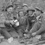 Royal Engineers serving with the 50th Division Beach Group share cocoa with a French boy in the village of Ver-sur-Mer, Gold area. (June 6, 1944). Source: Imperial War Museums, # B 5254.