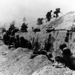 U.S. Soldiers of the 8th Infantry Regiment, 4th Infantry Division, move out over the seawall on Utah Beach after coming ashore. (June 6 or 9, 1944). Source: U.S. National Archives, U.S. Navy, SC 190062.