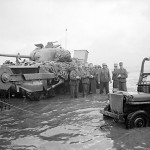 German prisoners awaiting transfer at the beaches of Normandy, France. A disabled Sherman Crab flail tank in background. (June 6, 1944). Source: Imperial War Museums, #4700-29 B 5089, Photographer:  J. Mapham.