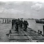 Soldiers coming ashore on a pontoon causeway built by the SeaBees. This causeway was laid down at Omaha Beach during the Normandy Invasion. Source: U.S. National Archives, # 6682629.