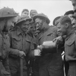 Lance Corporal Walter Ray, Royal Engineers, shares with other Beach Group personnel a bottle of rum he found floating in the sea, Gold area. (June 6, 1944). Source: Imperial War Museums, # B 5260.