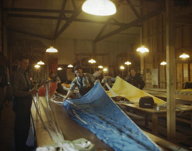 Royal Air Force parachute packers on an RAF glider station folding coloured parachutes for use by airborne troops during the Normandy invasion. Source: Imperial War Museums, # TR 1782.