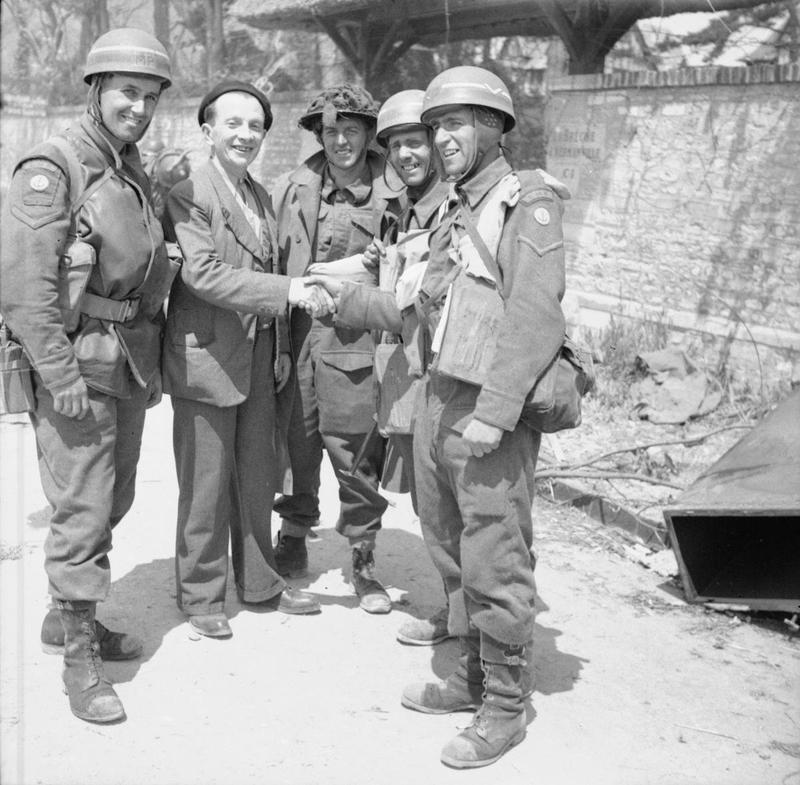 A French civilian greets British troops in La Brèche d'Hermanville. The 3 CMPs (Corps of Military Police) despatch riders are from No. 5 or 6 Beach Group, attached to 3rd Division. (June 6, 1944). Source: Imperial War Museums, # B 5028.