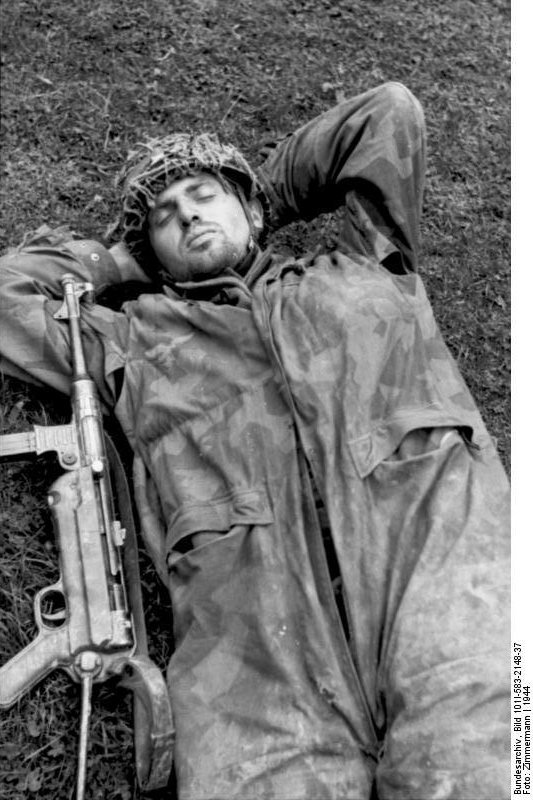 German paratrooper taking a nap with his MP 40 submachine gun at his side, Normandy, France. (1944). Source: German Federal Archive, Bild 101I-583-2148-37.