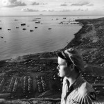 Lt. Ceil Dennis, atop Mount Suribachi on a July evening in 1945, looks out over the 21st Bomber Command installations and the ships anchored near the shore of Iwo Jima, Bonin Islands. (July 1945). Source: Mark, www.7thfighter.com.