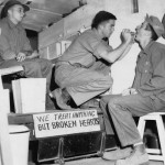Morning sick call in a 7th Fighter Command ambulance an Iwo Jima. The Medic is Cpl. Reaford B Williams, W/O Herman J. Diesel is the man being treated. In left background is Cpl Willard S Bennett. At extreme right (wearing glasses) is Cpl. Nolan Patterson. Source: Mark, www.7thfighter.com.