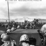 Fourth Division Marines begin an attack from the beach on Iwo Jima, as another boatload of men is disgorged onto the beach by an LCVP. Note the amphibious tractor (LVT) burning in the right center, and men taking cover ashore. (February 19, 1945). Source: Naval History and Heritage Command.