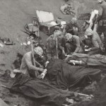U.S. Navy doctors and corpsmen administer to wounded Marines at an Iwo Jima first aid station. Navy Chaplain Lieutenant John H. Galbreath (right center) is kneeling beside a man who has severe flash burns, received in an artillery battery fifty yards or so away. (February 20, 1945). Source: Creative Commons.